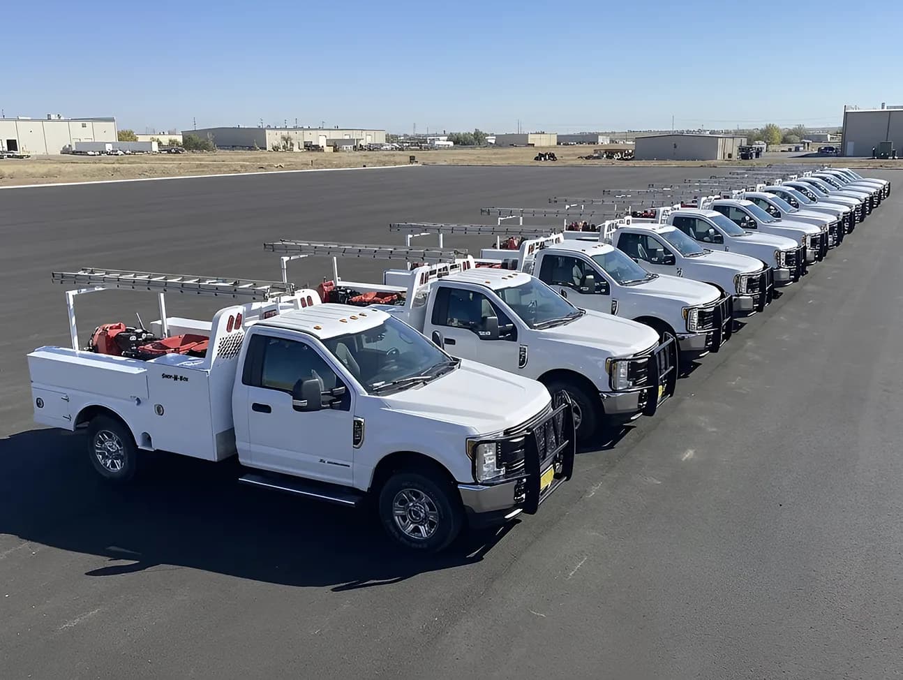 Fleet of white service trucks outfitted with Shop-N-Box™ roll-out truck toolbox organization systems