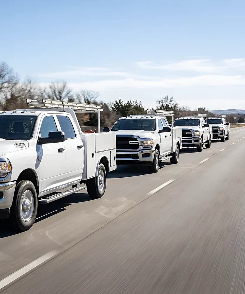 Fleet of white service trucks with Shop-N-Box tool storage systems